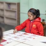 Child engaging in educational activity at school desk, promoting learning.